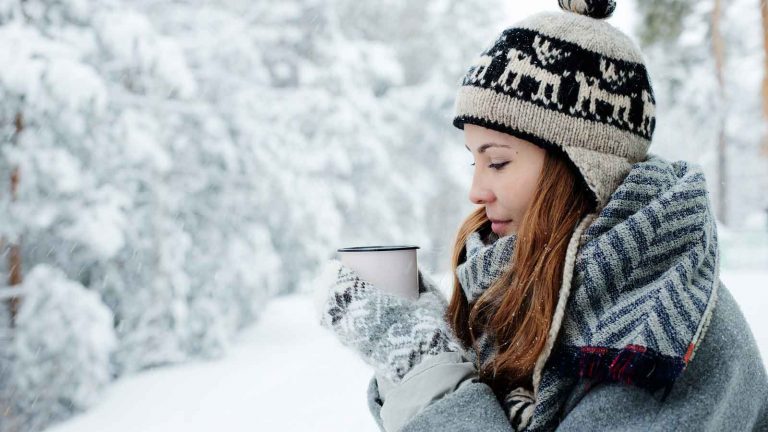 雪の中で飲み物を飲む女性