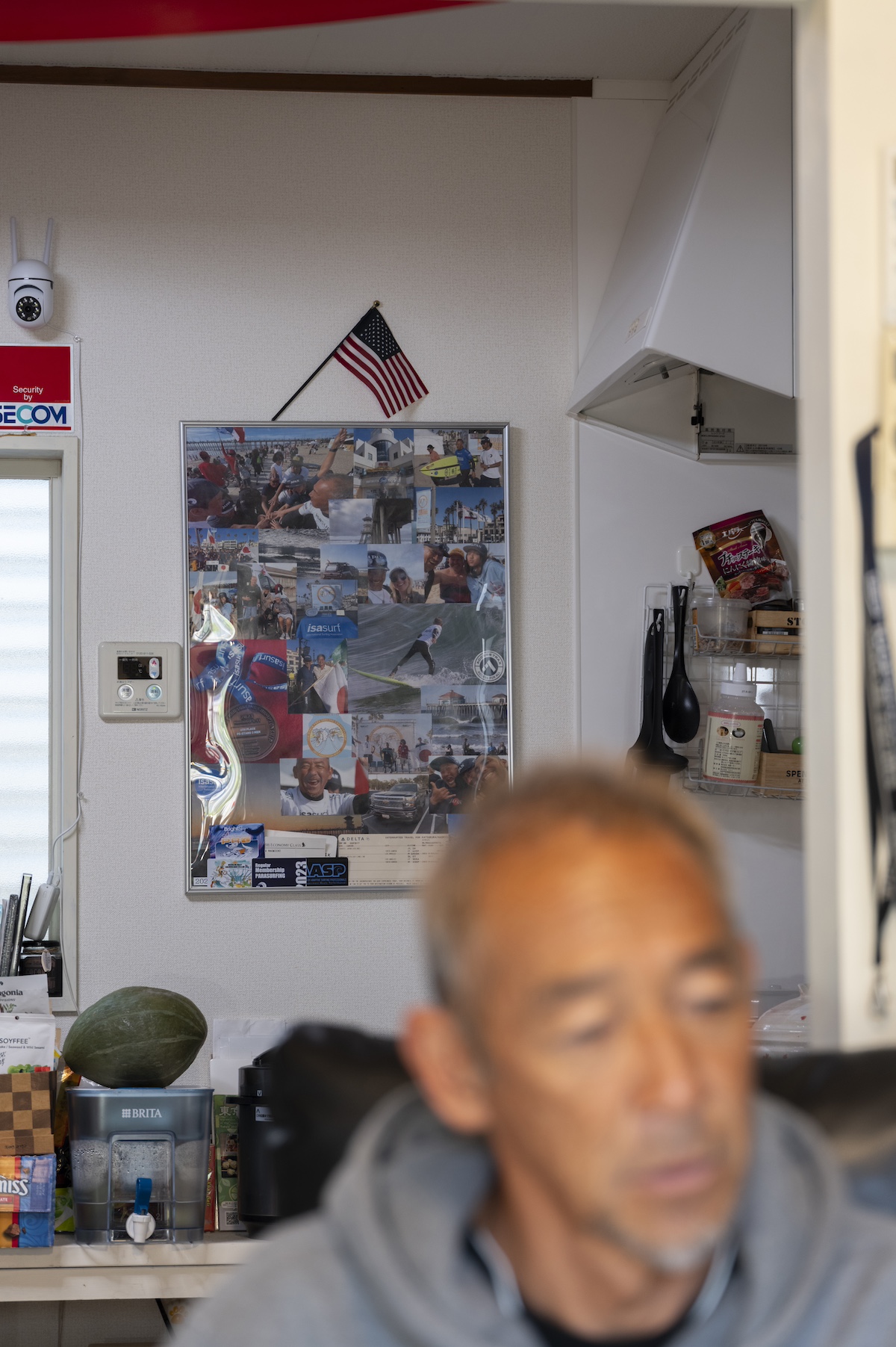 サーファー勝倉直道の後ろに、大会の思い出を詰め込んだ写真が飾られている