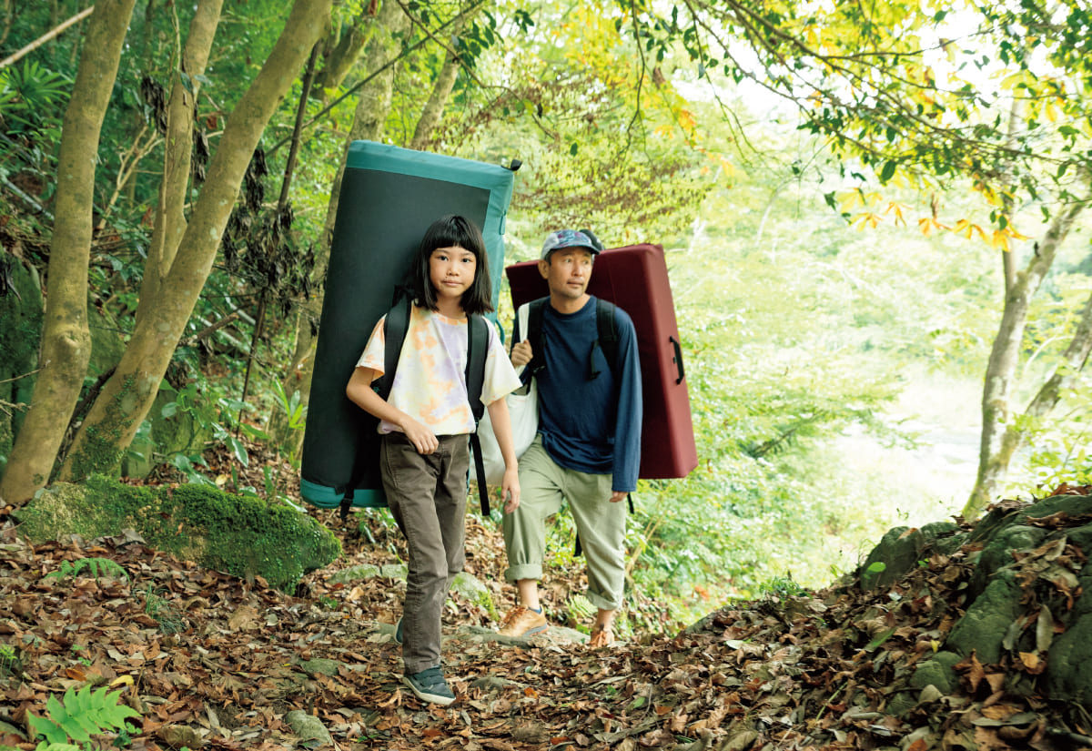 親子でボルダリングマットを持って山を登る画像