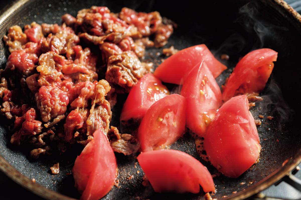牛肉を炒め、トマトを追加している様子