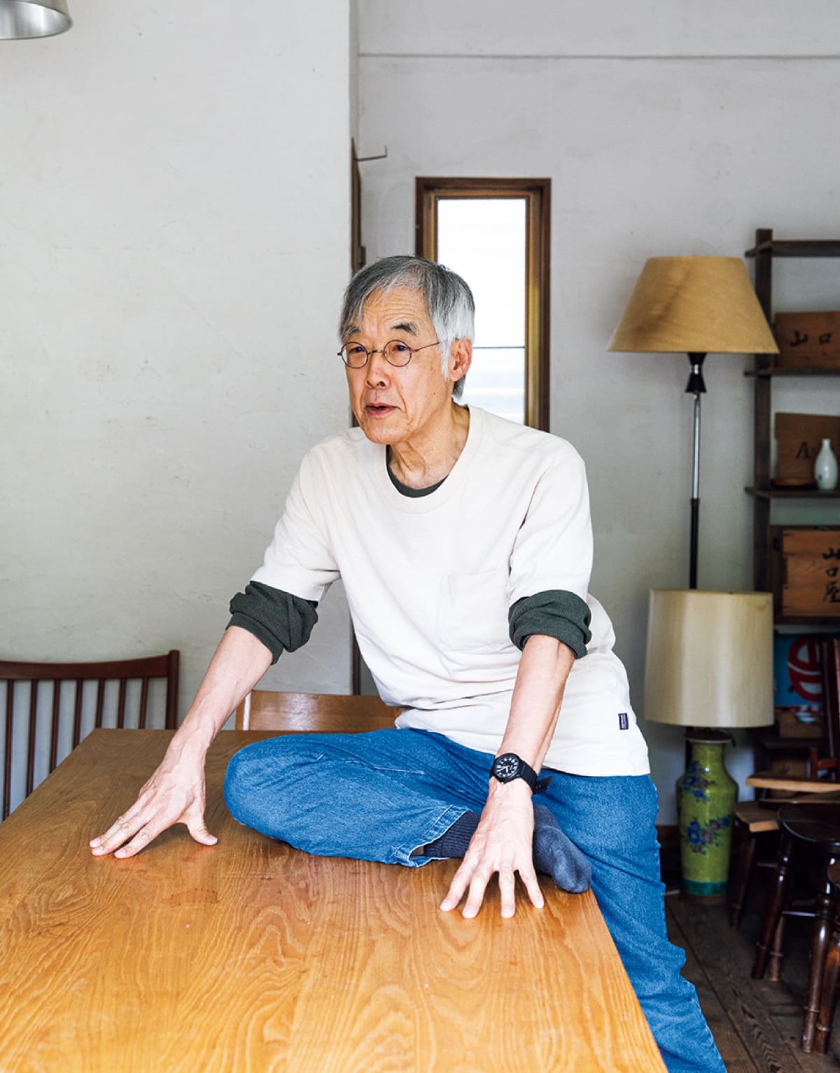 高橋源一郎さんがテーブルに腰をかけてストレッチをしている様子