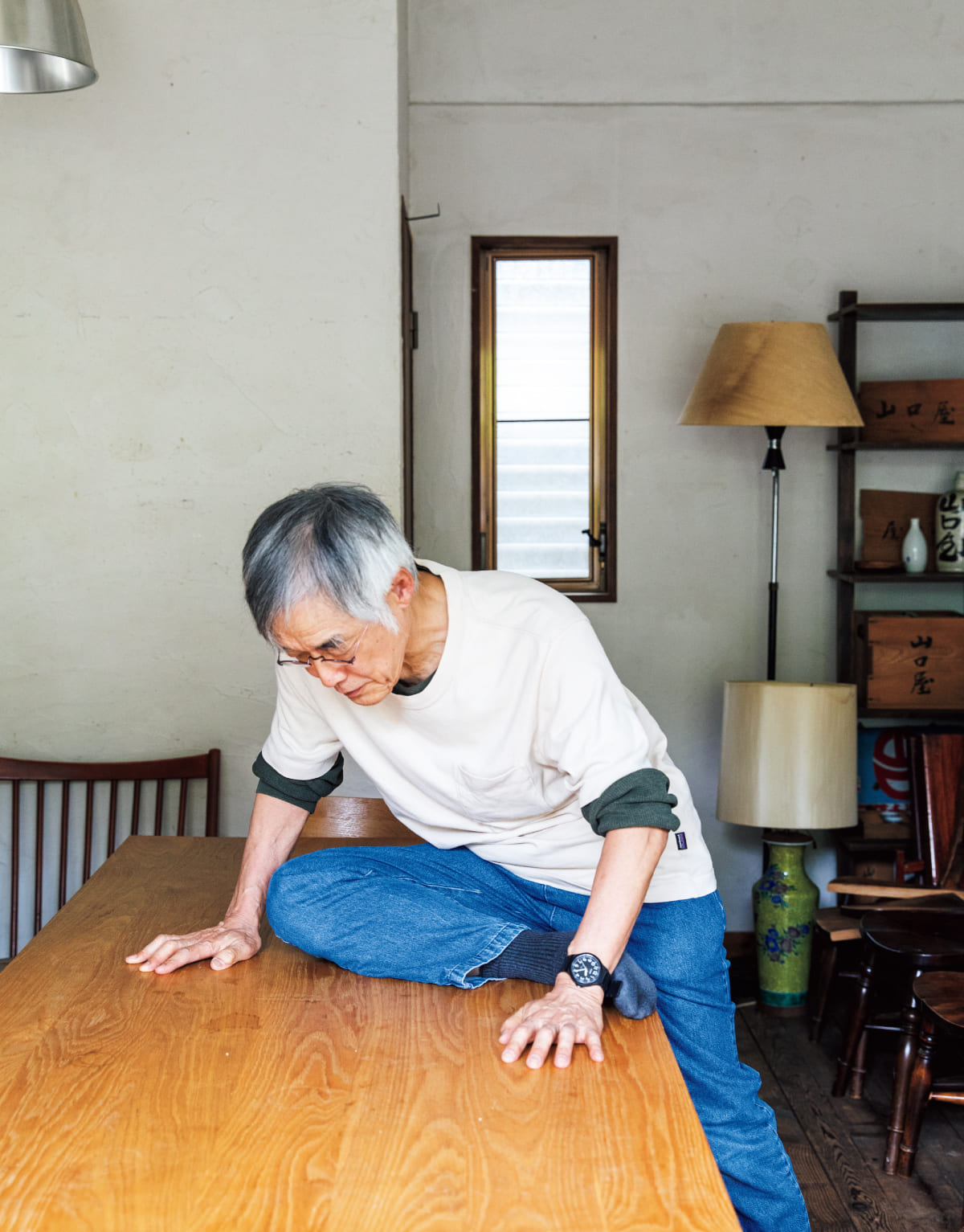 高橋源一郎さんがテーブルに腰をかけてストレッチをしている様子