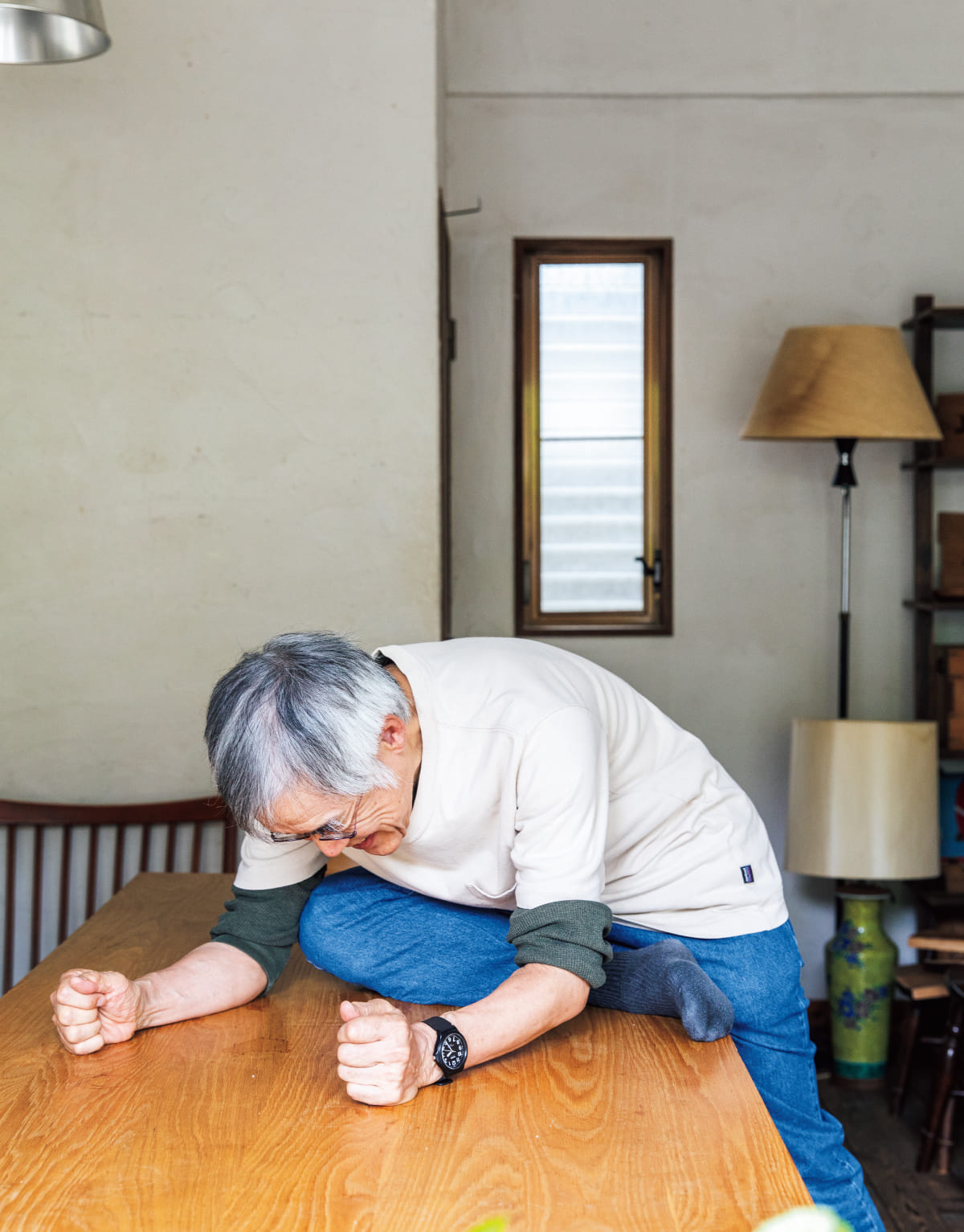 高橋源一郎さんがテーブルに腰をかけてストレッチをしている様子