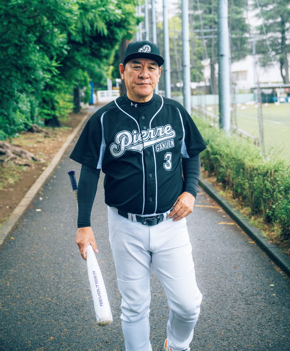 ピエール瀧さんが正面を向きユニフォーム姿でバッドを持っている
