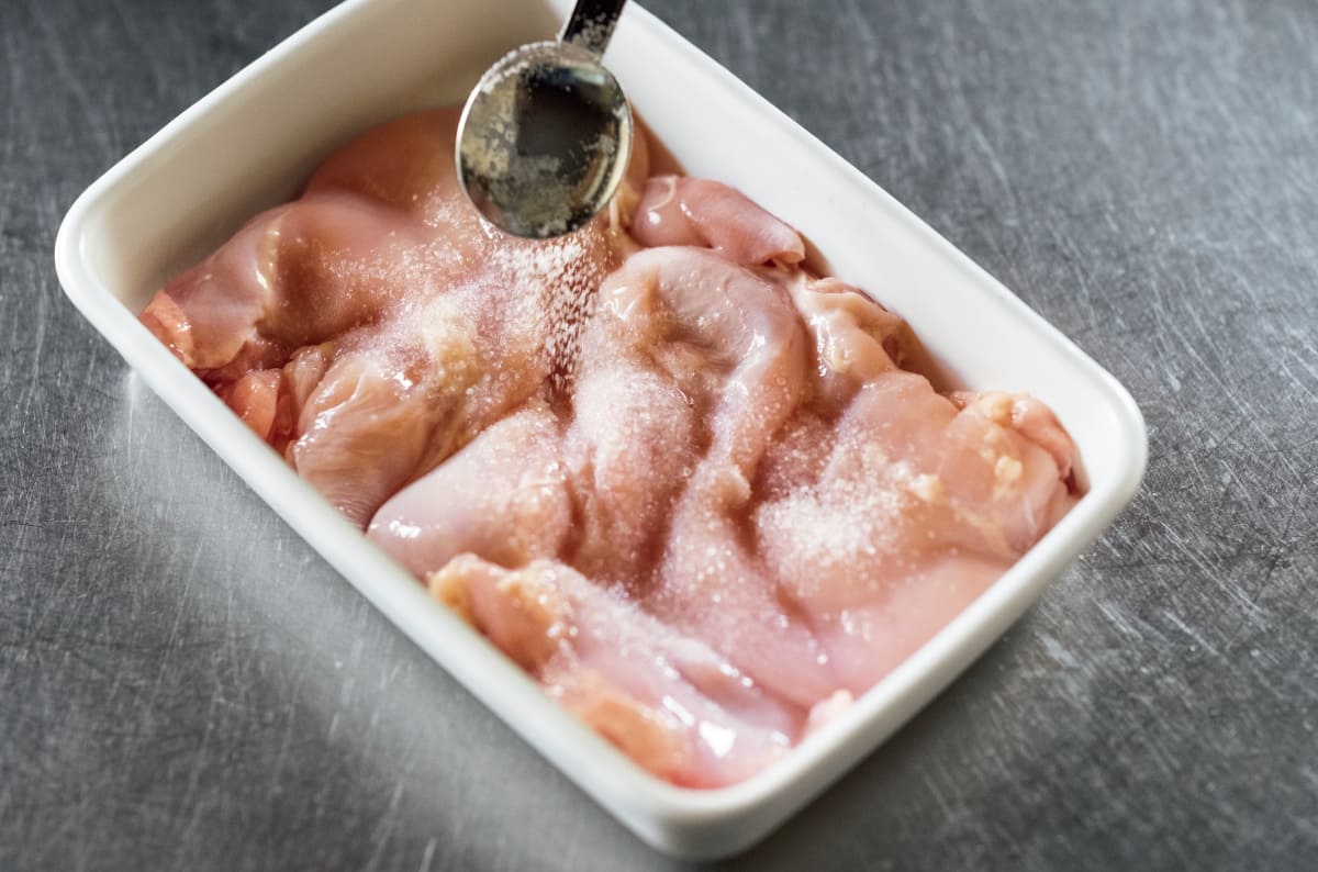 バッドに調味料と鶏肉を入れている様子