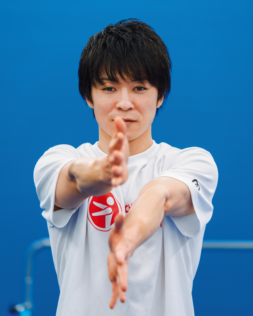 両手を顔の前で上下に並べるおなじみのポーズをとる内村航平さん