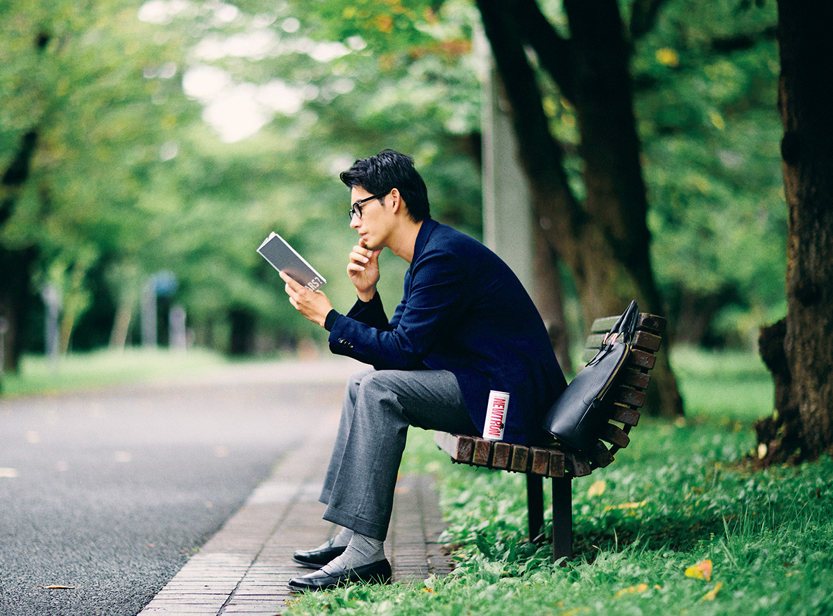 男性横に《NEWTRON》が置いてあり、ベンチでノートを読んでいる様子